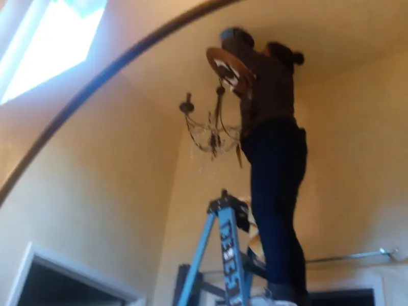 Electrician installing a chandelier in a Stow residence